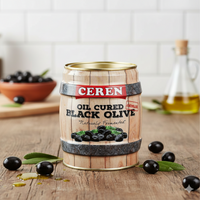 Cerén oil-cured black olive can on a wooden surface with olives and oil in the background.